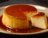 Crème renversée on a plate, with a slice cut out, glistening with caramel sauce.