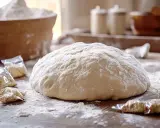 Pâte à brioche sur une table en bois, entourée de sachets de levure. Idéal pour savoir comment rattraper une pâte à brioche qui ne monte pas.
