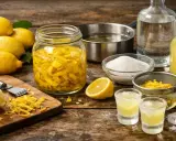 Préparation d'une recette avec limoncello : citrons, zestes, sucre, alcool et deux verres prêts à déguster.