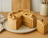Un délicieux gâteau moka à deux étages, garni de crème au café, d'amandes effilées et de grains de café. Une part est déjà coupée.