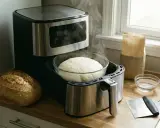 Pâte à pain levée dans un bol, prête à cuire dans une friteuse à air. Le temps pour faire lever une pâte au four est court, mais ici, elle est déjà prête.