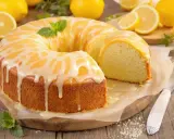 Un délicieux gâteau au citron, nappé d'un glaçage blanc et décoré de menthe fraîche. Une part a été coupée, révélant sa texture moelleuse.