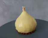 Délice en forme de poire, recouvert d'un glacage miroir jaune éclatant, sur un lit de crumble croquant, orné d'une touche de feuille d'or.