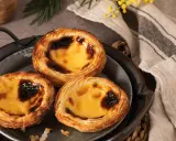 Trois délicieux pasteis de nata dorés, leur crème onctueuse légèrement caramélisée, sur un plateau en métal.