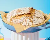 Pain maison doré dans une cocotte bleue, prêt à être dégusté. Le temps de cuisson pain 500g est parfait pour cette croûte craquelée.