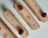 Quatre délicieux rectangles de crème chiboust ou diplomate, ornés de framboises fraîches et de feuilles d'or comestibles.