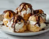 Des profiteroles gourmands, des petites boules de pâte à choux garnies de crème fouettée et nappées de chocolat noir fondant.