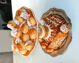 Une pièce montée de choux garnis de crème, nappés de caramel et décorés de perles blanches. Sur un plateau, d'autres choux et des tuiles aux amandes portent des inscriptions.
