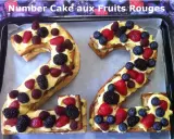 Un délicieux number cake aux fruits rouges, formant les chiffres 2 et 4, garni de crème pâtissière et de baies fraîches.