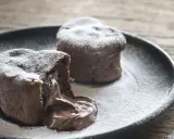 Deux coulants au chocolat inratables, saupoudrés de sucre glace, avec un cœur fondant qui déborde sur l'assiette.