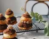 Délicieuses religieuses au chocolat, empilées sur une grille, ornées de crème et d'une touche de verdure.