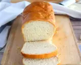 Un pain maison doré, tranché sur une planche en bois, parfait pour réussir son pain. La mie est aérée et la croûte appétissante.