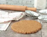 Pâte sablée prête pour la cuisson au four à chaleur tournante. Rouleau à pâtisserie, moules et torchon à proximité.