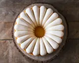 Un magnifique fondant pâtissier maison, orné de glaçage blanc nacré, sur un socle en bois rustique.