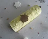 Une délicieuse bûche vanille, ornée d'une étoile en chocolat, sur un fond enneigé de noisettes et de flocons.