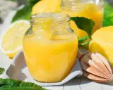 Un pot de crème au citron onctueuse, avec des citrons frais et une presse à bois. Parfait pour une tarte ou une crème dessert.