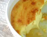 Un flan aux œufs à l'ancienne, doré et crémeux, servi dans un plat blanc sur une nappe texturée.