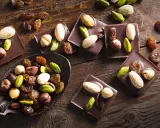 Carrés de chocolat noir Callebaut garnis d'amandes, noisettes, pistaches et raisins secs. Un délice à déguster !