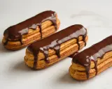 Trois éclairs au chocolat, parfaits pour une recette opera. La ganache dégouline sur la pâte à choux dorée.