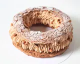 Un Paris Brest meilleur du chef, généreusement garni de crème pralinée et parsemé d'amandes effilées et de noisettes.