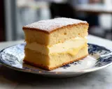 Tranche de gâteau moelleux, garnie d'une généreuse crème pâtissière et saupoudrée de sucre glace. Un délice !