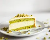 Tranche de gâteau végétalien à la pistache, garnie de pistaches concassées. Une délicieuse pâtisserie vegan.