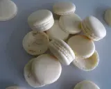 Des macarons blancs, certains assemblés, d'autres séparés, prêts pour la cuisson macaron chaleur tournante.