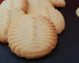 Un délicieux biscuit amande aux motifs striés, posé sur une surface sombre. Parfait pour accompagner un café.
