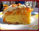 Tranche de gâteau moelleux avec des morceaux de pêche au sirop, nappage blanc et éclats d'amandes. Un délice fruité.