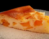 Tranche de clafoutis abricot, une création de chef, sur une assiette texturée.
