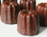 Plusieurs cannelés dorés, tout juste sortis du four, prêts pour la dégustation. La cuisson des cannelés révèle leur croûte caramélisée.