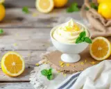 Délicieuse recette mousse au citron sans mascarpone, garnie de zestes et de menthe fraîche, sur fond de bois rustique.