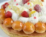 Un déliceux saint honoré framboise, orné de crème fouettée, de fruits rouges et de petites brioches caramélisées.