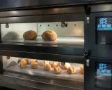 Deux étages de pains dorés dans un four professionnel. La fonction étuve four assure une cuisson parfaite.