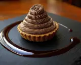 Délicieux Mont Blanc au chocolat, une recette gourmande à essayer. La crème onctueuse forme un cône parfait sur la tartelette.