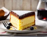 Tranche de gâteau génoise légère, garnie de chocolat et saupoudrée de sucre glace, accompagnée de baies et d'une touche de crème.