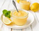 Un pot de crème citron onctueuse, garni de menthe fraîche et de quartiers de citron, prêt à être dégusté.
