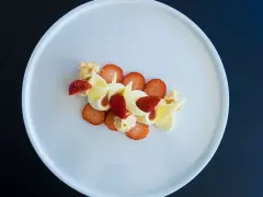 Délicieux dessert fraise melba, composé de fraises fraîches, de crème onctueuse et de copeaux de chocolat blanc, le tout présenté sur une assiette blanche.