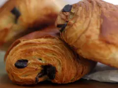Trois pains au chocolat dorés et feuilletés, prêts à être dégustés. Un délice qui nous rappelle d'où vient le pain au chocolat.