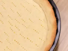 Pâte sablée dorée, piquée de petits trous, prête à être garnie pour une tarte délicieuse.