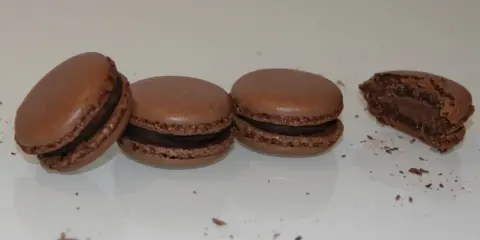 Trois macarons au chocolat et un croqué, parfaits pour une recette macaron chocolat.