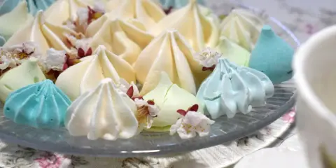 Meringues colorées, comme créées par un robot pâtissier, parsemées de fleurs délicates.