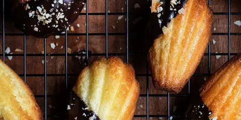 Des biscuits madeleine au chocolat, parsemés d'éclats d'amandes, refroidissent sur une grille. Un délice gourmand !