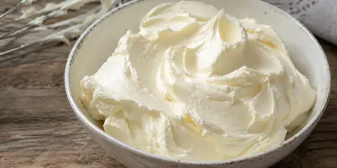 Un bol rempli de crème au beurre professionnelle, onctueuse et aérienne, prête à être utilisée pour des décorations pâtissières.