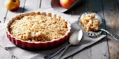 Un délicieux crumble aux pommes, avec sa pâte à crumble croustillante dorée, prêt à être dégusté.