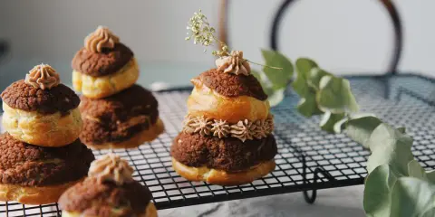 Délicieuses religieuses au chocolat, empilées sur une grille, ornées de crème et d'une touche de verdure.
