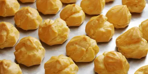 Une fournée de choux à la crème dorés, prêts pour la cuisson. Ils attendent patiemment d'être transformés en délices.