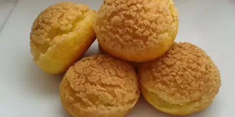 Quatre choux craquelin dorés et croustillants, prêts à être garnir.