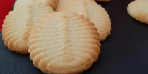 Un délicieux biscuit amande aux motifs striés, posé sur une surface sombre. Parfait pour accompagner un café.