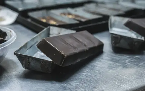 Une tablette de chocolat posée sur une petite boîte métallique. Idéal pour apprendre comment faire des copeaux de chocolat.